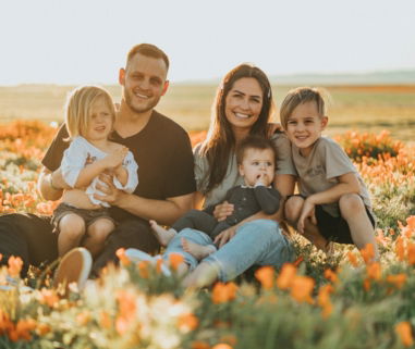 3 women and 2 men sitting on green grass field during daytime